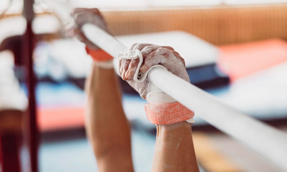 Gymnast's chalked hands gripping the uneven bars at Viswajit Nikhath Gymnastiks